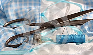 Spool of Blue Thread, Thimble and Needle on Blue and White Fabric