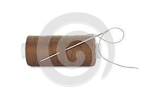 Spool of brown sewing thread with needle isolated on white