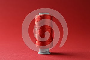 Spool of colorful sewing thread on red background