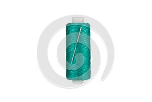 Spool of green thread and a threaded needle.