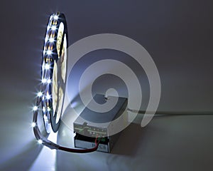 Spool of luminous LED strip light connected to Power Supply.