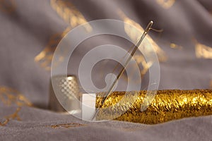 Spool of Metallic Gold Thread on Gray and Gold Fabric
