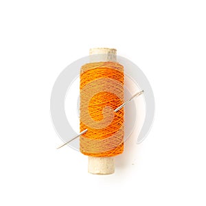 Spool of orange thread with needle isolated on white