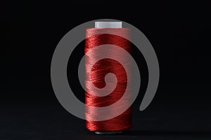 Spool of red sewing thread on black background