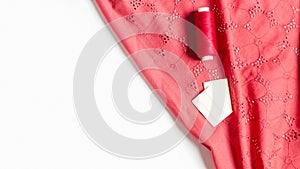 Spool of red thread on crumpled cotton fabric. Fashion and sewing concept. Tailoring. Women`s hobby. Copy space