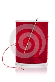 Spool of red thread and needle on white