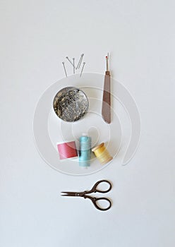 Spool threads, pins in round jar, seam ripper and small scissors on white