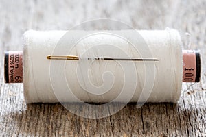 Spool of white thread with a needle