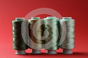 Spools of colorful sewing threads on red background
