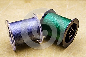 Spools of cords on the background of tarpaulin. Green and gray fishing line. Spools of braided fishing line