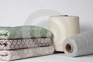 Spools with light thread and cotton cloth on a white isolated background. Textile and yarn industry concept