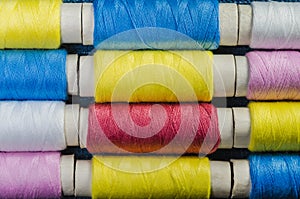 Spools of multi-colored threads arranged in rows
