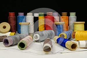 Spools with multi-colored threads on black background, close-up shot