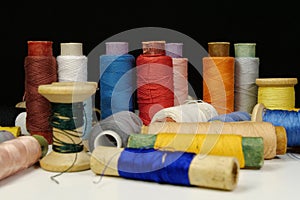 Spools with multi-colored threads on black background, close-up shot