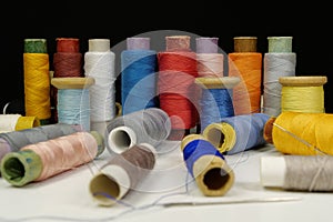 Spools with multi-colored threads on black background, close-up shot