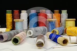 Spools with multi-colored threads on black background, close-up shot