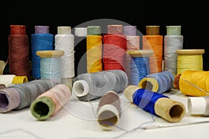 Spools with multi-colored threads on black background, close-up shot
