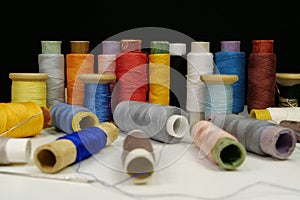 Spools with multi-colored threads on black background, close-up shot
