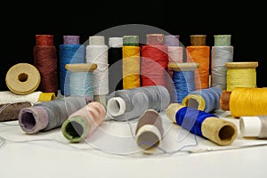 Spools with multi-colored threads on black background, close-up shot