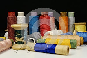 Spools with multi-colored threads on black background, close-up shot