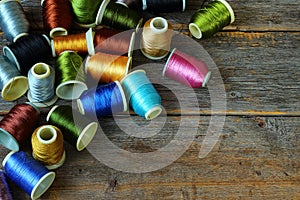 Spools of multicolored threads on wooden background
