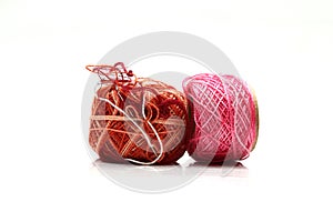 Spools of pink and brown thread and needle isolated on white background