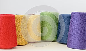 Spools of rainbow lgbt colors wool yarn for hand and machine knitting on a white background