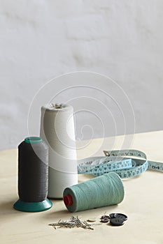 Spools of thead pins and measuring tape on table photo