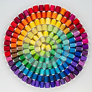 Spools of thread arranged in a circular pattern create a vivid rainbow