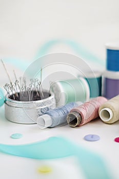 Spools of thread and basic sewing tools including pins, needle, a thimble, and tape measure. Copy space