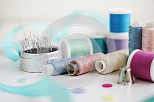 Spools of thread and basic sewing tools including pins, needle, a thimble, and tape measure