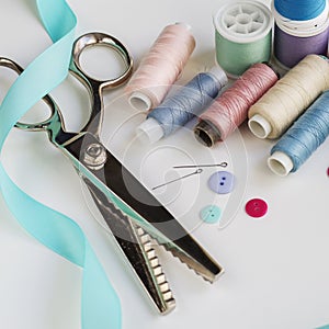 Spools of thread and basic sewing tools including pins, needle, a thimble, and tape measure. Copy space