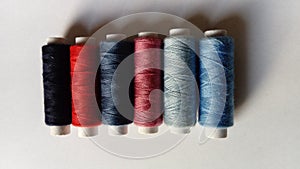 Spools of thread for machine sewing in different colors - red, pink, blue, gray, purple, blueberry, black