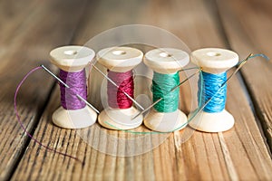 Spools of thread with needles on wooden background. Old sewing a