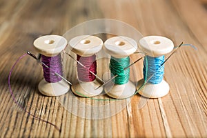 Spools of thread with needles on wooden background. Old sewing a