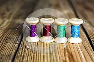 Spools of thread with needles on wooden background. Old sewing a