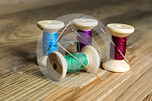 Spools of thread with needles on wooden background. Old sewing a