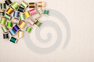 Spools of Thread that are vintage and colorful.  A flat layout on off white linen fabric background with copy space