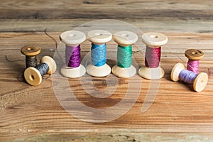 Spools of thread on wooden background. Old sewing accessories. photo