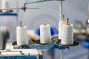 Spools of white threads on sewing machine, closeup