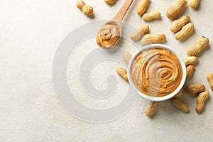 Spoon and bowl with peanut butter, and peanut on white background