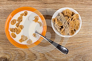 Spoon in bowl with yogurt, multicereal flakes, bowl with flakes