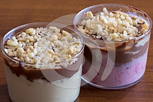 Spoon cake with two creams and almonds, two desserts in transparent glasses