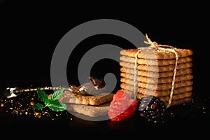 Spoon with chocolate cream and cookies, mint, berries and crumbs isolated on black background