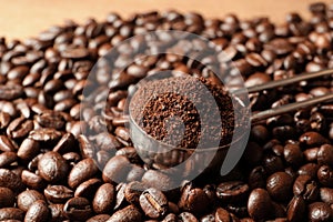 Spoon with coffee grounds and roasted beans on table