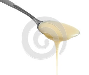 Spoon with condensed milk on white background. Dairy product