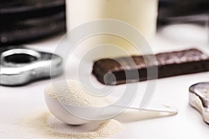 Spoon with Creatine, whey or casein, whey supplements, protein bar for physical exercises, gym in the background, muscle mass gain