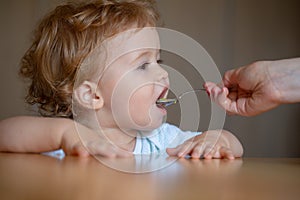 Spoon feeding baby. Mother giving healthy food to her adorable child at home. Feeding kids.