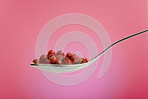 Spoon filled with rose peppers