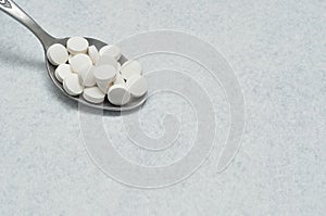 A spoon filled with white tablets